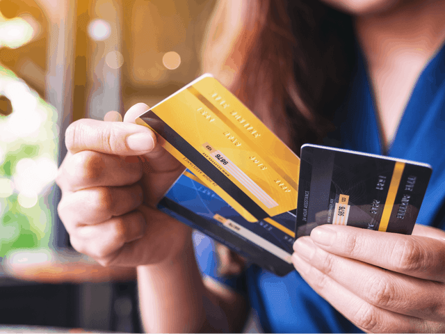 Imagem de uma mulher com três cartões de crédito na mão, representando nosso conteúdo sobre cartão de crédito aprovado na hora