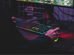 Imagem de uma pessoa jogando jogos em um computador gamer, com o teclado colorido e luz neon. Foto usada para ilustrar o conteúdo sobre consórcio gamer
