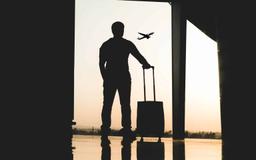 Imagem de um homem segurando uma mala em um aeroporto, ilustrando nosso conteúdo sobre consórcio de viagens