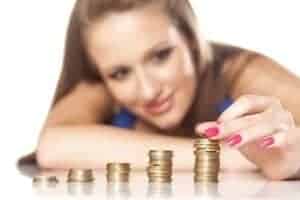 Mulher empilhando moedas e pensando como economizar dinheiro
