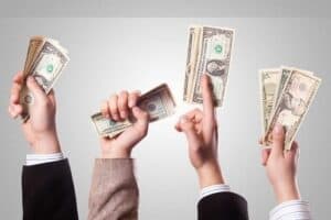Mãos segurando dólares simbolizando o tema Como ganhar dinheiro sem sair de casa