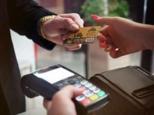pessoas realizando uma transação financeira por meio de uma adquirente (máquina de cartão).