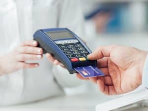 Imagem de uma pessoa passando o cartão de crédito em uma maquininha, ilustrando nosso post sobre cartão bloqueado por erro de senha
