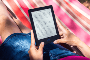 Pessoa deitada em uma rede lendo um e-book para simbolizar o tema Aplicativo de livros