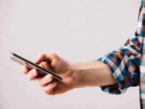 Confira os TOP 10 SuperApps do Prêmio iBest na categoria Finanças e Economia close em mão de celular segurando celular representando TOP 10 SuperApps do Prêmio iBest 2020