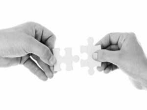 uma mão de cada lado segura uma peça de quebra-cabeça para ver se elas se encaixam, representrando o conceito de suitability