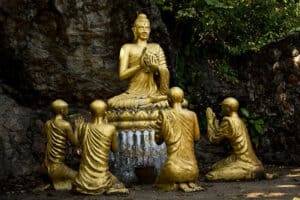 estatua budista dourada em Laos com uma figura central e outras 4 reverenciando a que está em evidência