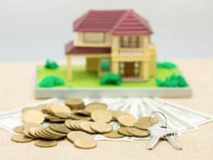 miniatura de casa e moedas, representando investir em imóveis em 2021