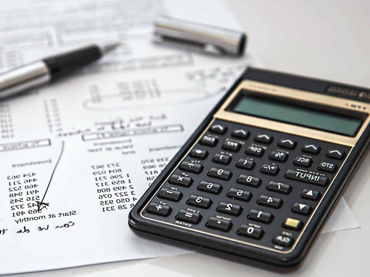 Imagem de uma calculadora, caneta e documentos, simbolizando o conteúdo sobre a calculadora de salário anual