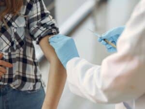 enfermeiro aplicando vacinacao contra covid 19 no braço de pessoa