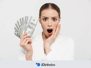mulher com expressão surpresa segurando notas de dinheiro em referência a o que é dividendo