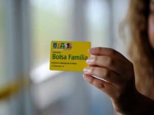 mão feminina segurando cartão do Bolsa Família representando aumento no valor do Bolsa Família