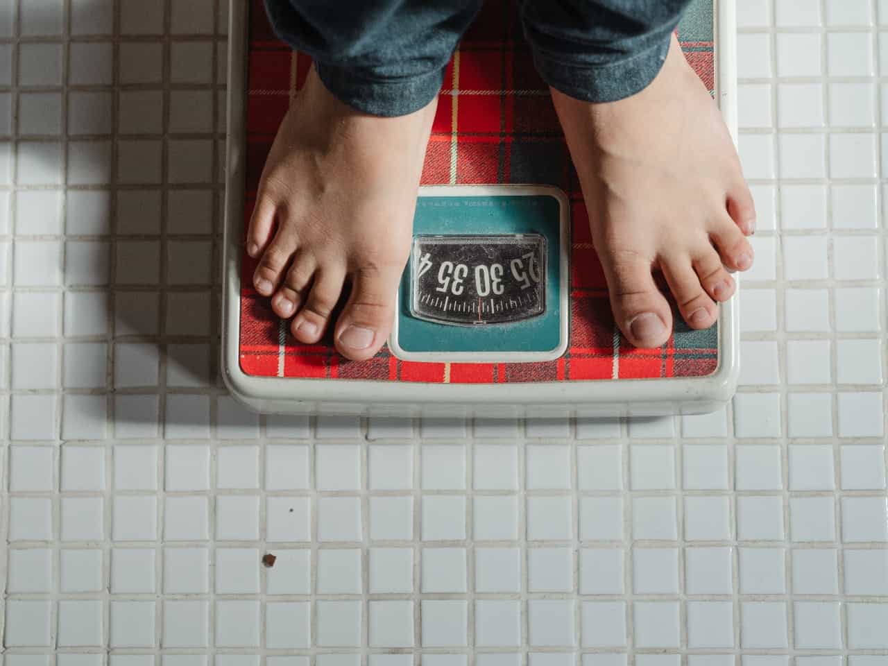 Imagem de uma pessoa em cima de uma balança, buscando calcular o peso ideal