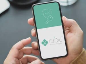 Mãos segurando um smartphone com a interface do PIX, representando PIX saque e troco