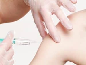 pessoa tem uma seringa na mão e vai vacinar o braço de outra pessoa para ganhar o desconto no seguro de vida para vacinados