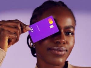 modelo com cartão nubank próximo ao rosto representando ação de aumento de limite de cartão de crédito