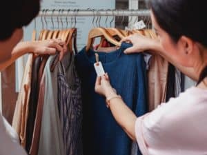 imagem de duas pessoas olhando roupas num cabide de loja para ilustrar o artigo sobre curso de vendas