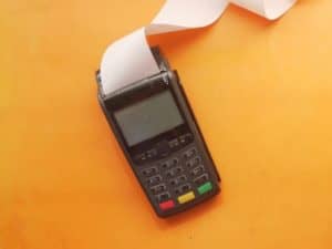 imagem de uma máquina de cartão de crédito numa mesa laranja para ilustrar o artigo sobre qual a melhor maquininha de cartão
