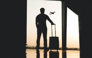 Imagem de um homem segurando uma mala em um aeroporto, ilustrando nosso conteúdo sobre consórcio de viagens