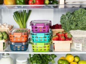 Imagem de uma prateleira em uma casa com vários legumes e frutas. Entre eles, vemos alguns potes coloridos, que ilustram o tema do nosso conteúdo, que é sobre consórcio Tupperware