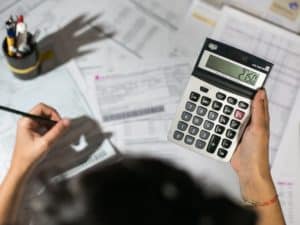 Imagem de uma pessoa utilizando uma calculadora, caneta e papel. Imagem utilizada para ilustrar uma notícia sobre o aumento da taxa Selic.