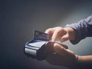 Imagem de uma pessoa utilizando uma maquininha de cartão. Imagem utilizada para ilustrar uma notícia sobre dicas para evitar dívidas no cartão.