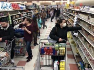 Imagem de algumas pessoas no supermercado, fazendo compras de diferentes produtos com carrinhos. Imagem utilizada para ilustrar uma notícia sobre a reduflação. Crédito: Boston Globe via Getty Images