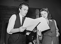Dois atores em frente a um microfone lendo suas falas.