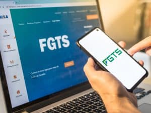 Imagem de um celular e um computador com a logotipo do FGTS (Fundo de Garantia por Tempo de Serviço). Foto utilizada para ilustrar uma notícia sobre a consulta do lucro FGTS