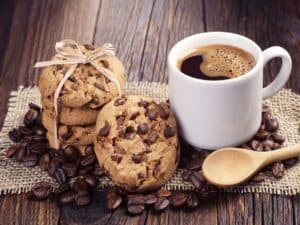 Grãos de café, cookies e uma xícara de café representando uma franquia de cafeteria