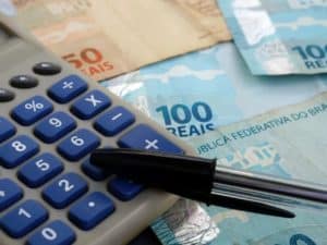 Imagem de três notas de 100 reais e uma calculadora. Foto utilizada para ilustrar uma notícia sobre o empréstimo pronampe.