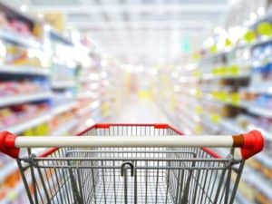 Imagem de um supermercado desfocado com um carrinho de compras. Foto utilizada para ilustrar uma notícia sobre a inflação IPCA julho. Crédito: Shutterstock.