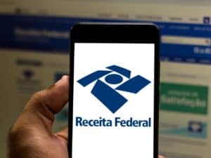 Imagem de um celular com a logo da Receita Federal. Foto utilizada para ilustrar uma notícia sobre a correção da tabela do Imposto de Renda. Créditos: rafapress/Shutterstock