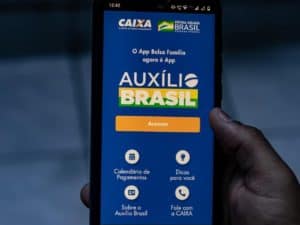 Imagem de um celular com o aplicativo do Auxílio Brasil. Foto utilizada para ilustrar uma notícia sobre o empréstimo do Auxílio Brasil. Crédito: Tharlys Fabricio/Shutterstock