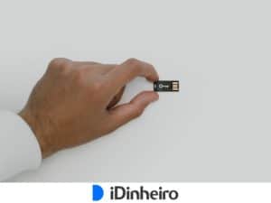 pulso com camisa de manga branca e mão segurando um dispositivo preto, com linhas de chip e um símbolo branco de chave
