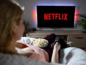 Imagem de uma pessoa assistindo netflix em uma televisão enquanto come pipoca. Foto utilizada para ilustrar uma notícia sobre o plano com anúncios da Netflix. Crédito: Shutterstock