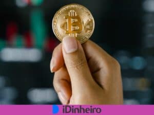 mão segurando uma moeda dourada com símbolo do Bitcoin fundido