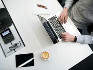 imagem de uma pessoa usando notebook em uma mesa com café para o texto sobre melhor conta digital PJ