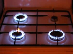 Imagem de um fogão com três chamas acesas. Foto utilizada para ilustrar uma notícia sobre o calendário do Auxílio-Gás 2023. Crédito: Unsplash.