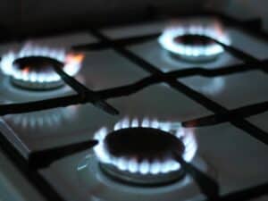 Imagem de um fogão com as chamas acesas utilizada para ilustrar uma notícia sobre o cadastro do Auxílio Gás. Crédito: Unsplash