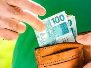Imagem de uma carteira com algumas cédulas d 100 reais utilizada para ilustrar uma notícia sobre o saque do dinheiro esquecido. Crédito: Shutterstock