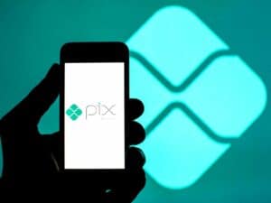 Mão segurando um celular com a logotipo do PIX. Foto utilizada para ilustrar uma notícia sobre pagamento via PIX. Crédito: SOPA Images/LightRocket via Getty Images