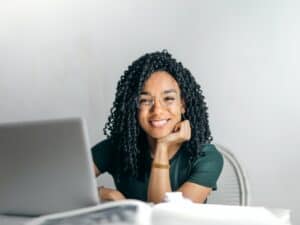 mulher negra sorrindo e comprando em um marketplace por meio de seu laptop