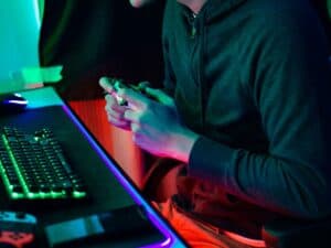 pessoa sentada em uma cadeira gamer com um teclado com luzes