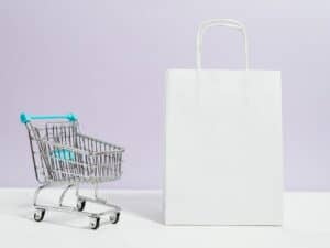 um mini carrinho de compras e uma sacola branca representando os fornecedores de dropshipping nacional