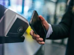 Imagem de uma pessoa realizando um pagamento com o celular. Foto utilizada para ilustrar uma notícia sobre o tap to pay da Apple, que permite usar o iPhone como maquininha de cartão. Crédito: Unsplash.