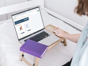 mulher mexendo em computador portátil com um caderno em cima