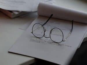 óculos redondos sobre um bloco de papel