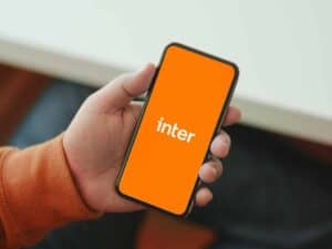 Pessoa segurando celular com a imagem do Banco Inter na tela para simbolizar o tema Telefone do Banco Inter